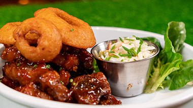 bbq wings with onion rings and coleslaw on the side