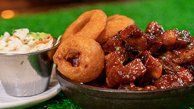 bbq wings with onion rings and coleslaw on the side